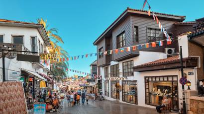 Ruelle historique d’Uzun Çarşı à Kaleiçi, avec maisons traditionnelles en bois et drapeaux internationaux dans la vieille ville d’Antalya